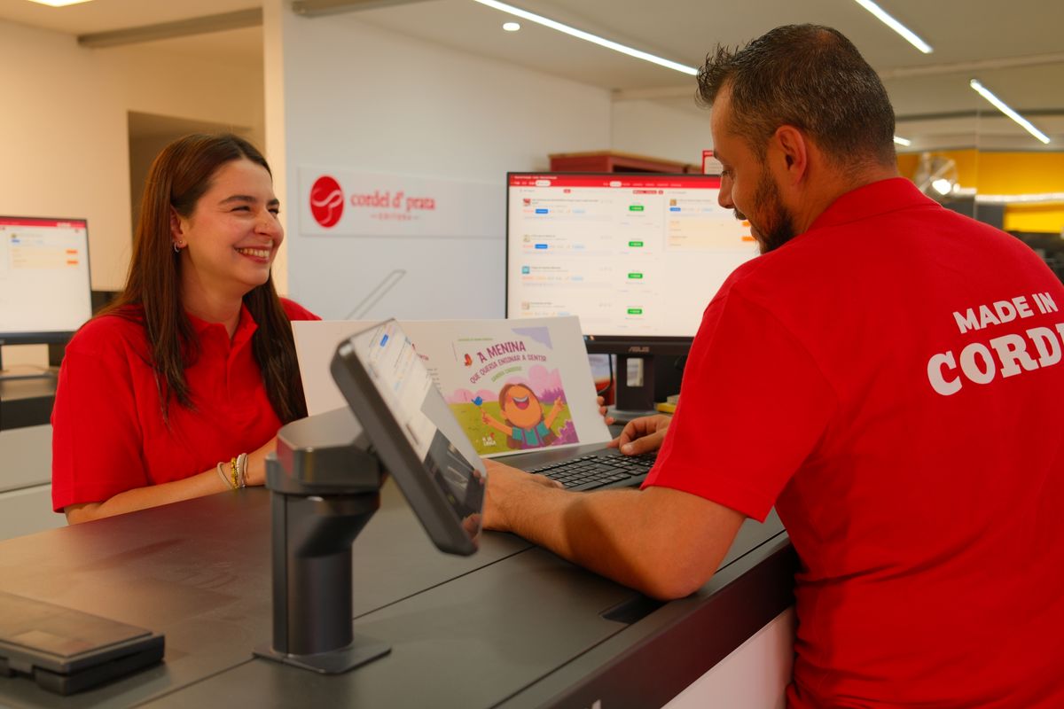 Dois elementos da equipa a conferir uma prova na consola da gráfica