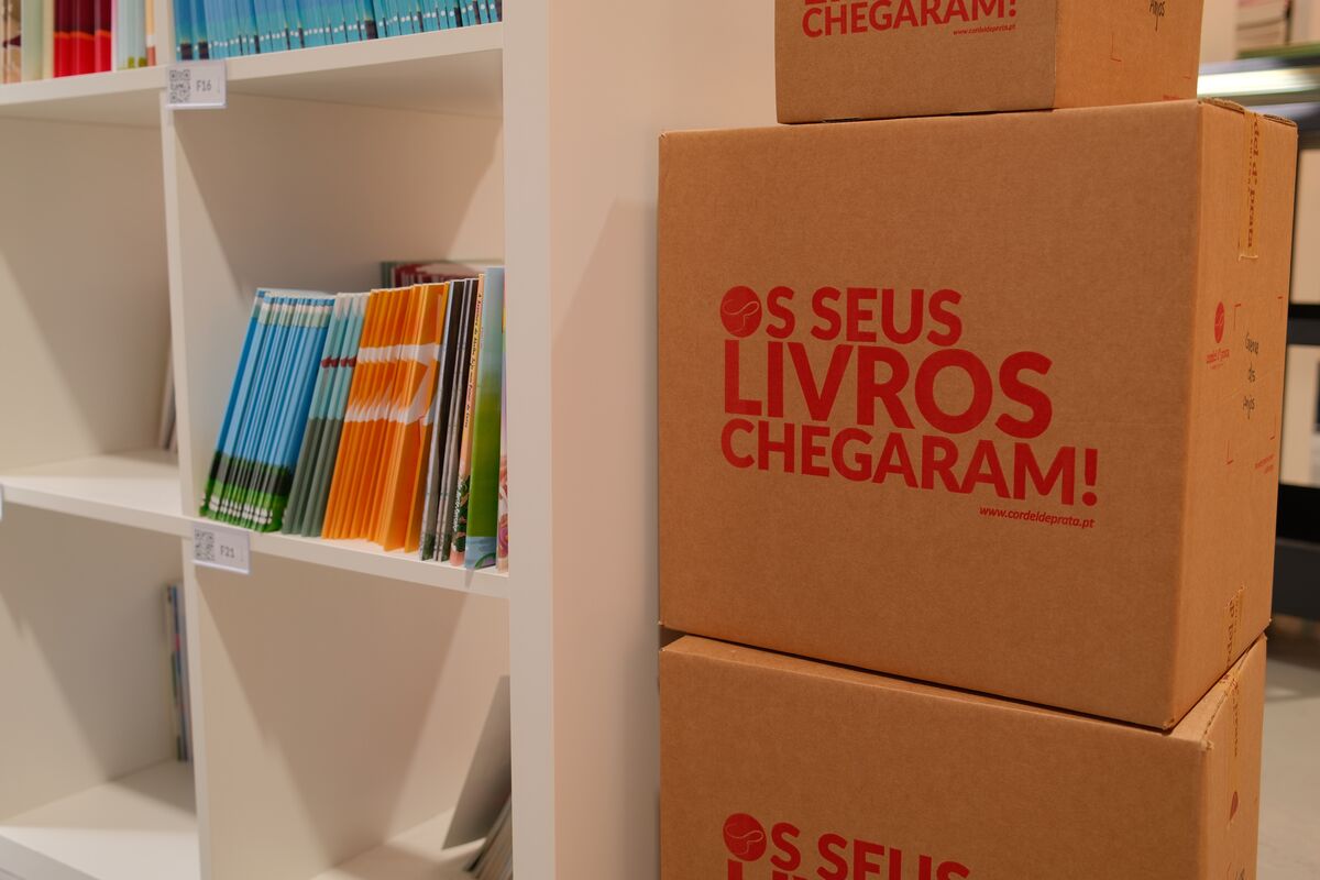 Caixas de expedição com a marca «Os seus livros chegaram», junto às estantes