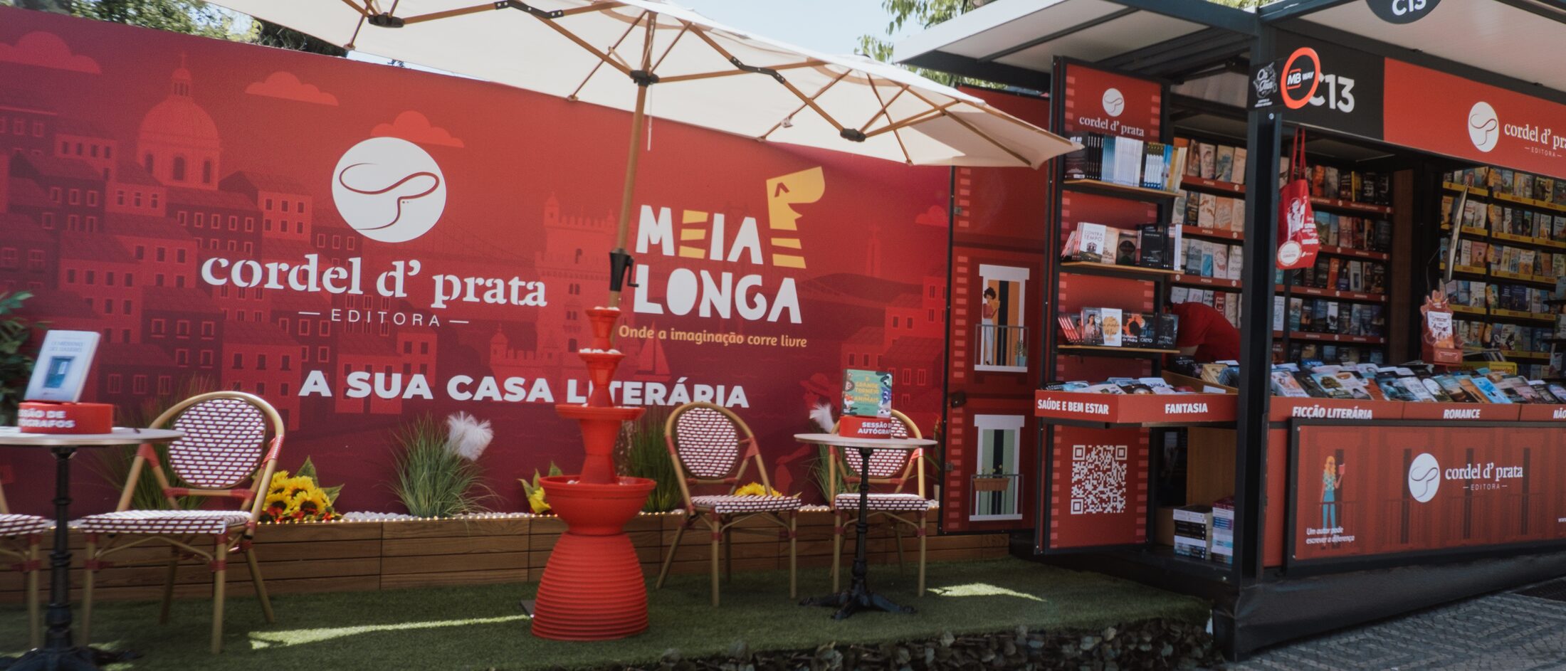 Pavilhão da Cordel D' Prata na feira do livro, com as estantes cheias e mesas para sessões de autógrafos